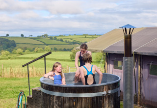 Drie kinderen genieten van een buitenbad bij BoerenBed Billingsmoor Farm vakantiepark in Zuidwest-Engeland.