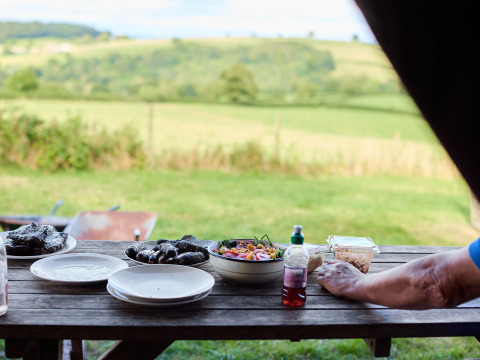 Picknicktafel met eten en borden op Billingsmoor Farm, uitkijkend over het groene Engelse platteland.