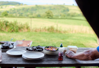 Table de pique-nique rustique avec plats à Billingsmoor Farm, vue sur la campagne verdoyante derrière.