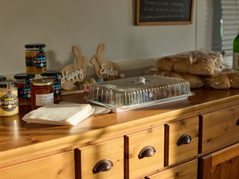Potjes honing, marmelade, broodjes en servetten op een houten blad bij BoerenBed Foxglove farm, Engeland.