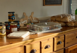 Potjes honing, marmelade, broodjes en servetten op een houten blad bij BoerenBed Foxglove farm, Engeland.