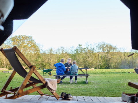 Een gezin zit samen aan een picknicktafel bij BoerenBed Foxglove farm, Zuid-Oost Engeland, op het gras.