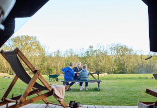 Een gezin zit samen aan een picknicktafel bij BoerenBed Foxglove farm, Zuid-Oost Engeland, op het gras.