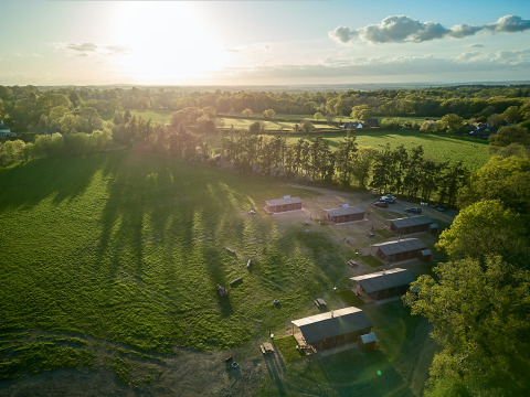 Luchtfoto van BoerenBed Foxglove farm vakantiepark in Zuidoost-Engeland met groene velden en hutten.
