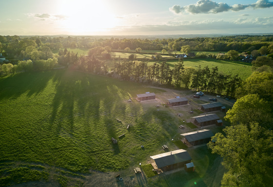 Luchtfoto van BoerenBed Foxglove farm vakantiepark in Zuidoost-Engeland met groene velden en hutten.