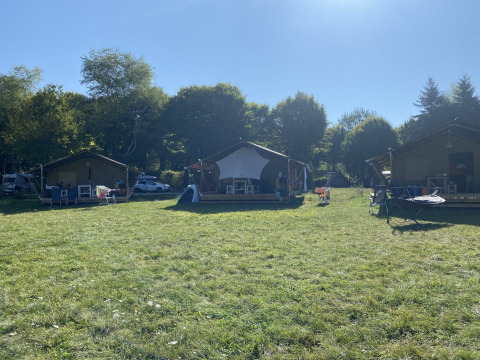 Drei Safarizelte auf dem Campingplatz La Faz in Frankreich, von Bäumen und grüner Wiese umgeben.