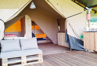 Foto dell'interno di una tenda safari di lusso al campeggio La Faz in Francia, con divano pallet e cucina.