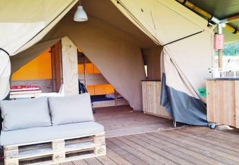 Foto interior de una tienda safari de lujo en el camping La Faz en Francia, con sofá de palets y cocina.