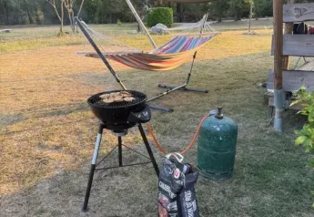 Outdoor view at Lodgetent XL with barbecue, charcoal bag, hammock and gas cylinder at Campsite La Faz, France.