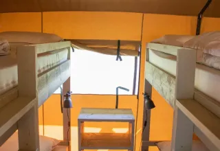 Interior of Lodgetent XL with bathroom at Campsite La Faz in France, featuring wooden bunk beds.