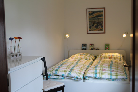 Slaapkamer in lodge 'Am Strand' in Duitsland met twee bedden, geruite dekbedden en eenvoudige decoratie.
