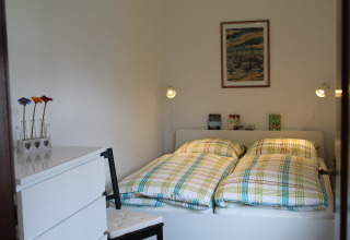 Slaapkamer in lodge 'Am Strand' in Duitsland met twee bedden, geruite dekbedden en eenvoudige decoratie.
