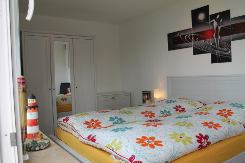 Slaapkamer in lodge 'Am Strand' in Duitsland met bloemenbedsprei en vuurtorendecoratie.