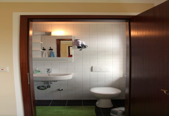 Kleine badkamer bij lodge «Am Strand» in Duitsland met wasbak, toilet en spiegel tegen witte tegels.