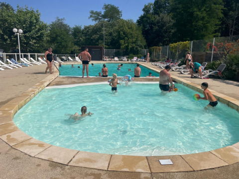 Famiglie si rilassano e nuotano nella piscina del campeggio La Digue in Auvergne-Rhône-Alpes, Francia.