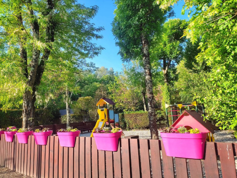 Parco giochi con vasi colorati su una recinzione, circondato da alberi al campeggio La Digue in Francia.