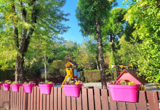 Parco giochi con vasi colorati su una recinzione, circondato da alberi al campeggio La Digue in Francia.