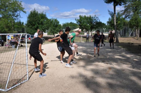 Ragazzi e adolescenti giocano a calcio su un campo di ghiaia al campeggio La Digue in Alvernia-Rodano-Alpi, Francia.