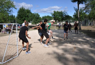 Ragazzi e adolescenti giocano a calcio su un campo di ghiaia al campeggio La Digue in Alvernia-Rodano-Alpi, Francia.