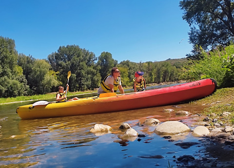 Famiglia in kayak sul fiume, immersa nella natura e sotto il cielo azzurro al campeggio La Digue.