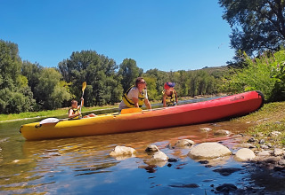 Famiglia in kayak sul fiume, immersa nella natura e sotto il cielo azzurro al campeggio La Digue.