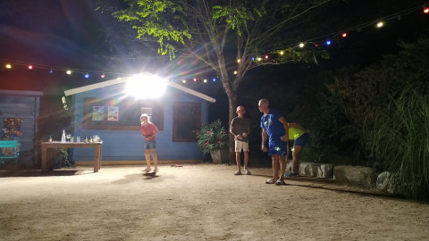 Quattro persone giocano a pétanque di notte in un campeggio in Auvergne-Rhône-Alpes, Francia.