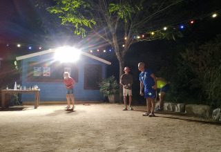 Quattro persone giocano a pétanque di notte in un campeggio in Auvergne-Rhône-Alpes, Francia.