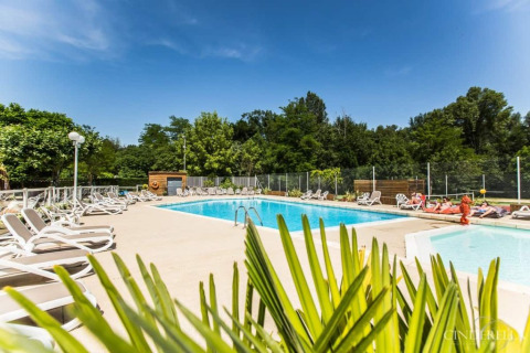 Piscina all'aperto con lettini e alberi verdi al campeggio La Digue in Auvergne-Rhône-Alpes, Francia.