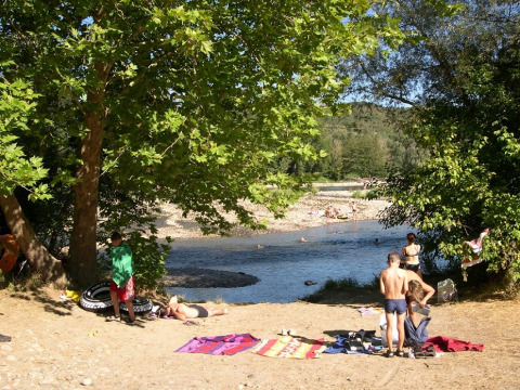 Campeggiatori si godono il sole e il fiume alberato al campeggio La Digue, parco vacanze in Francia.