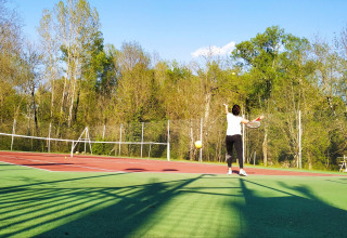 Due persone giocano a tennis su un campo all'aperto circondato da alberi al campeggio La Digue in Francia.