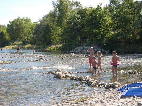 Bambini e adulti giocano nel fiume poco profondo al campeggio La Digue in Auvergne-Rhône-Alpes, Francia.