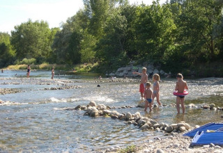Bambini e adulti giocano nel fiume poco profondo al campeggio La Digue in Auvergne-Rhône-Alpes, Francia.