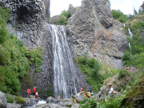 Persone si godono la natura e la cascata tra le rocce al campeggio La Digue in Alvernia-Rodano-Alpi, Francia.