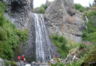 Persone si godono la natura e la cascata tra le rocce al campeggio La Digue in Alvernia-Rodano-Alpi, Francia.