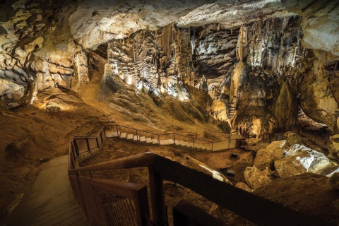 Interno di una grotta illuminata vicino a Ruoms, Auvergne-Rhône-Alpes, con scale e straordinarie formazioni rocciose.