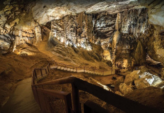Interno di una grotta illuminata vicino a Ruoms, Auvergne-Rhône-Alpes, con scale e straordinarie formazioni rocciose.