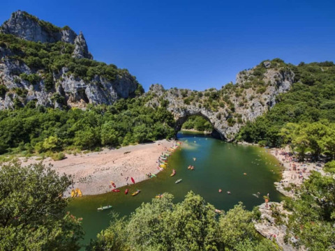 Vista sul fiume Ardèche con arco naturale e colline verdi vicino a Ruoms, Auvergne-Rhône-Alpes, Francia.
