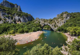 Vista sul fiume Ardèche con arco naturale e colline verdi vicino a Ruoms, Auvergne-Rhône-Alpes, Francia.