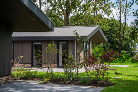 Moderna casa de campo Villa Veldzicht con revestimiento de madera y jardín verde en un día soleado.
