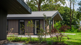 Modern Villa Veldzicht lodge with wood siding, large windows, and a landscaped garden on a sunny day.