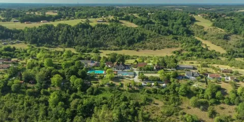 Vista aerea del campeggio Les Terrasses de Dordogne in Nouvelle-Aquitaine, Francia, tra colline verdi.
