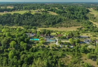 Vista aerea del campeggio Les Terrasses de Dordogne in Nouvelle-Aquitaine, Francia, tra colline verdi.