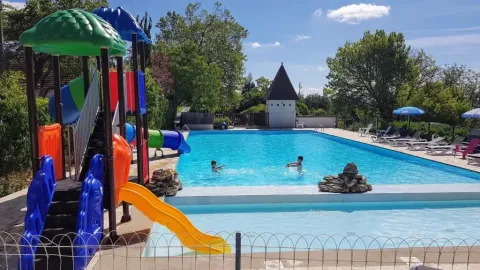 Area giochi e piscina del campeggio Les Terrasses de Dordogne, villaggio vacanze in Nouvelle-Aquitaine, Francia.