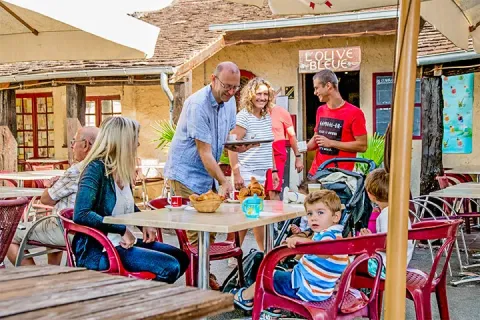 Famiglie che si godono un pasto sulla terrazza al campeggio Les Terrasses de Dordogne in Francia.