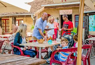 Famiglie che si godono un pasto sulla terrazza al campeggio Les Terrasses de Dordogne in Francia.