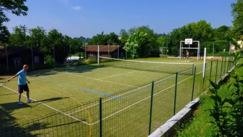 Campo multisport con rete da tennis e canestro presso Les Terrasses de Dordogne, villaggio vacanze in Francia.