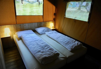 Habitación con dos camas individuales y lámparas en una Lodgetent met badkamer en Les Terrasses de Dordogne, Francia.