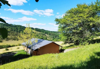 Tente safari Lodgetent met badkamer au camping Les Terrasses de Dordogne, France, entourée de collines verdoyantes.