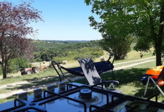 Blick aus einem Safarizelt mit Bad auf Campingplatz Les Terrasses de Dordogne, Wiesen und Traktor.