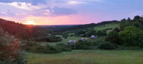 Sonnenuntergang über Hügeln und Safarizelten des Campingplatzes Les Terrasses de Dordogne in Frankreich.